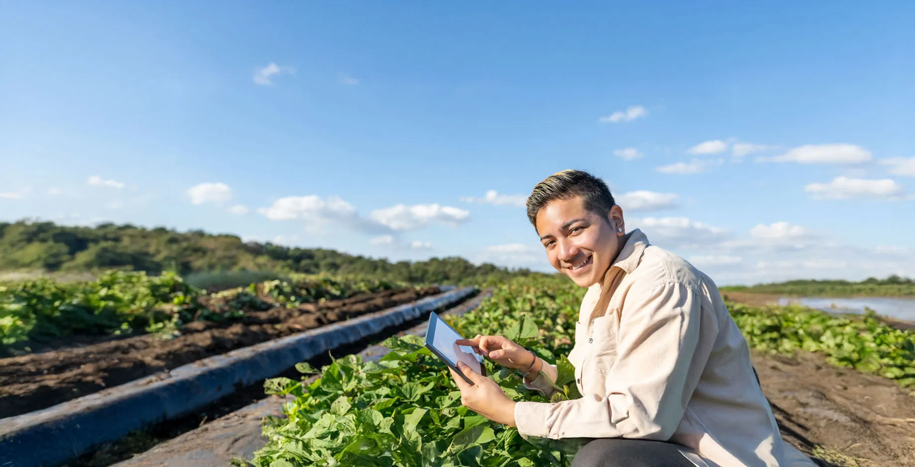 Un jeune homme porte à sa main une tablette connectée dans un champ. Un exemple d'agriculture numérique ?