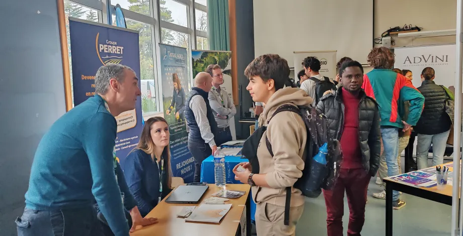 Un étudiant se renseigne sur un stand d'entreprise